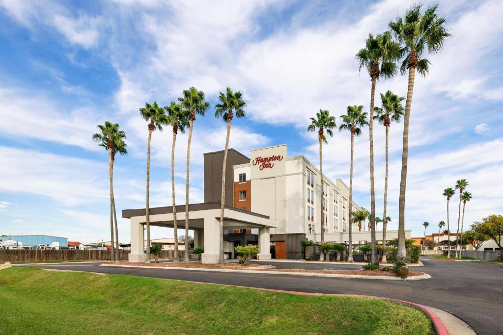 a hotel with palm trees in front of a building at Hampton Inn Laredo in Laredo