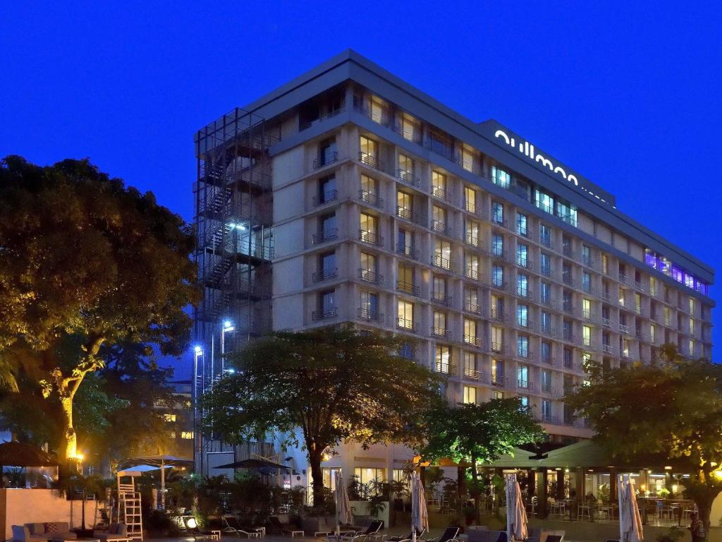 a tall building with a lot of windows at night at Pullman Kinshasa Grand Hotel in Kinshasa