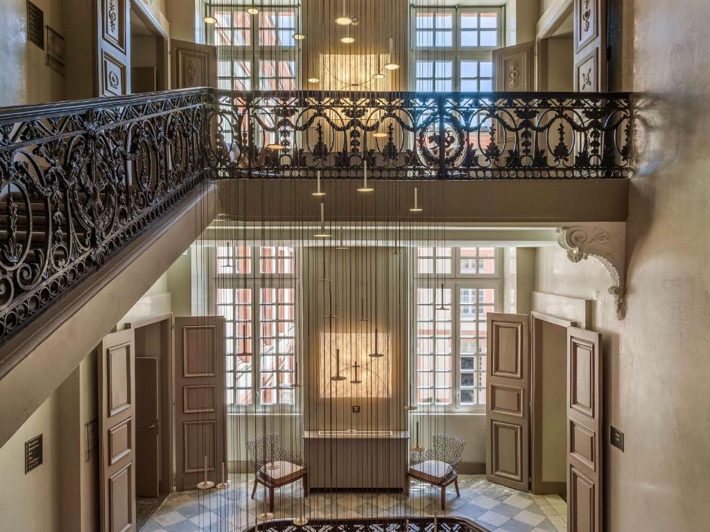 a staircase in a building with windows and a stair case at La Cour des Consuls Hotel and Spa Toulouse - MGallery in Toulouse