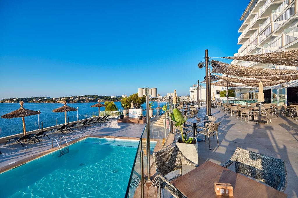 une piscine avec des chaises et des tables ainsi qu'un bâtiment dans l'établissement Hotel Florida Magaluf - Adults Only, à Magaluf