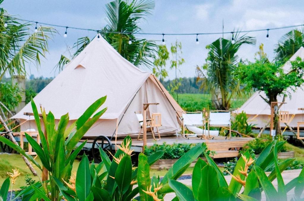 une grande tente blanche dans un champ arboré dans l'établissement Sky Camping, à Củ Chi