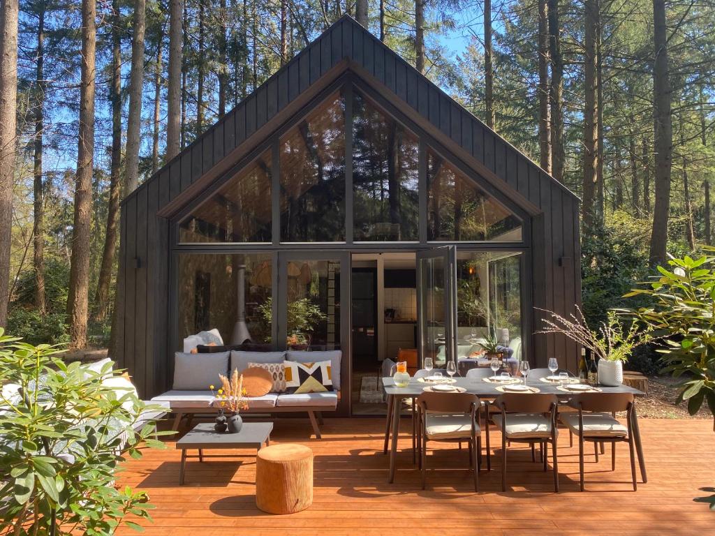 una casa de cristal en el bosque con mesa y sillas en Fantastisch luxe boshuis I Onthaasten in de natuur en Emst