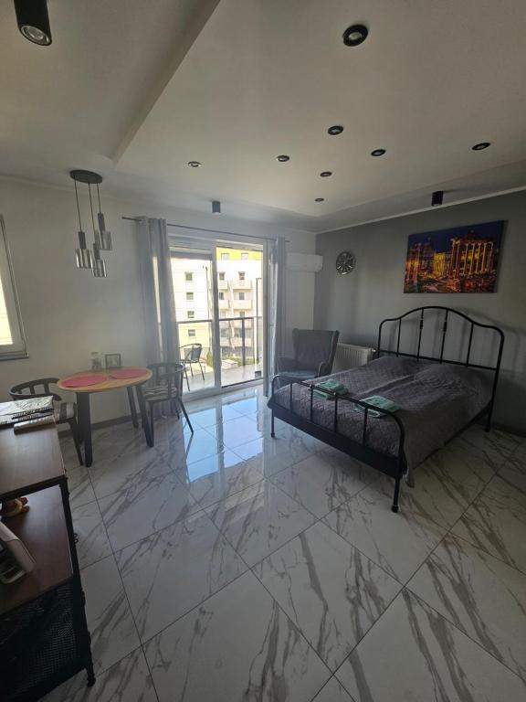 1 dormitorio con 1 cama y sala de estar con mesa en Apartament Malta en Poznan