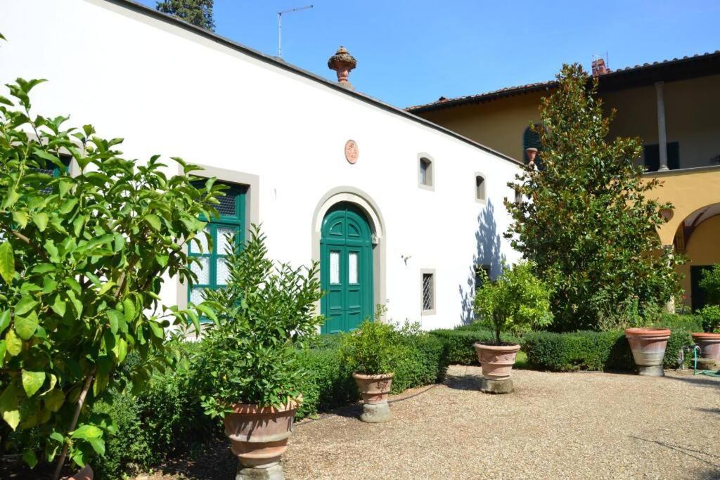 ein weißes Gebäude mit grüner Tür und einigen Pflanzen in der Unterkunft Villa Luciano in Lastra a Signa