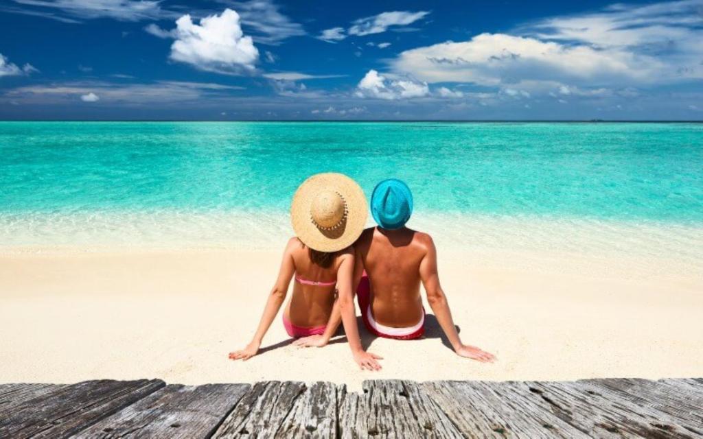 Due persone sedute su una spiaggia con l'oceano di Madi Grand Maldives a Fulidhoo