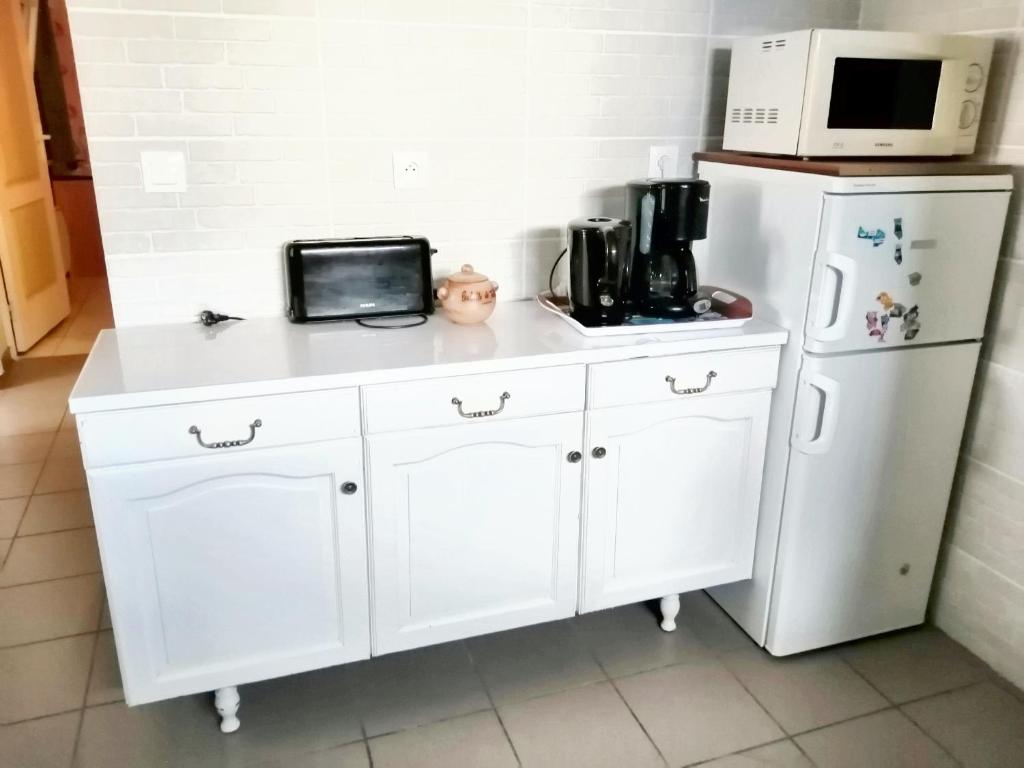 eine Küche mit weißen Schränken, einer Mikrowelle und einem Kühlschrank in der Unterkunft Maison de 2 chambres avec jardin clos et wifi a Tredaniel in Trédaniel