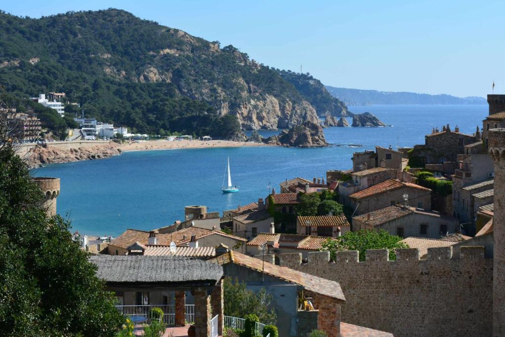 a view of a town with a sail boat in the water at Nautic wifi Parking y a 150 metros de la playa in Tossa de Mar