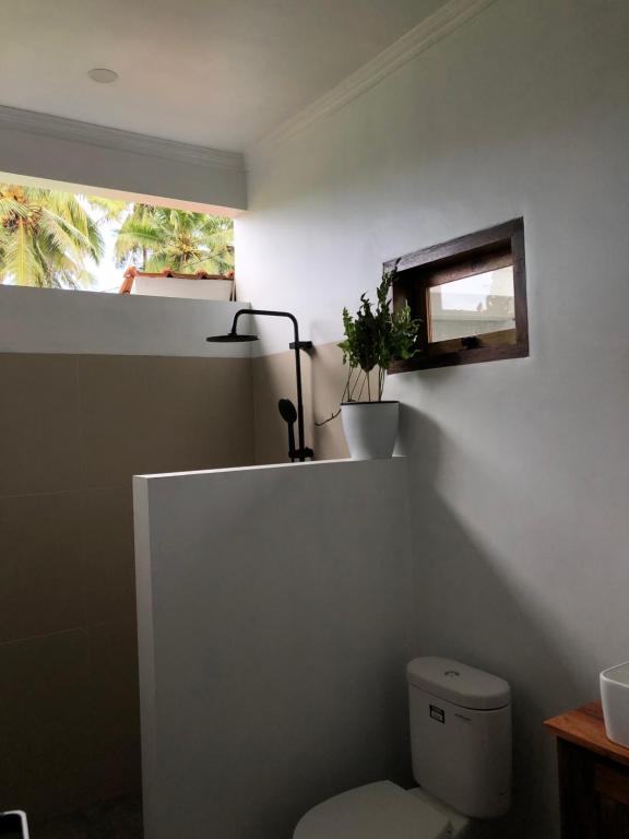 バツカラスにあるRumah Markisa Batukarasのバスルーム(窓、植物付きのトイレ付)