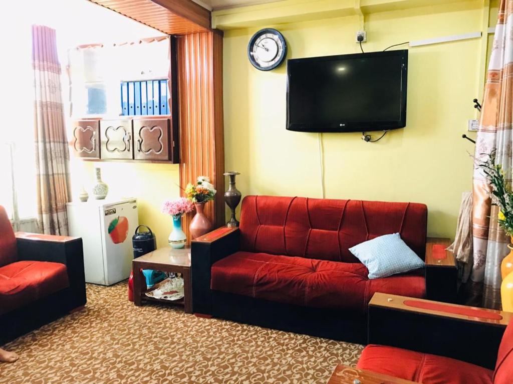 a living room with a red couch and a tv at Millat Hotel & Noor Jahan Hotel Kandahar in Kandahār