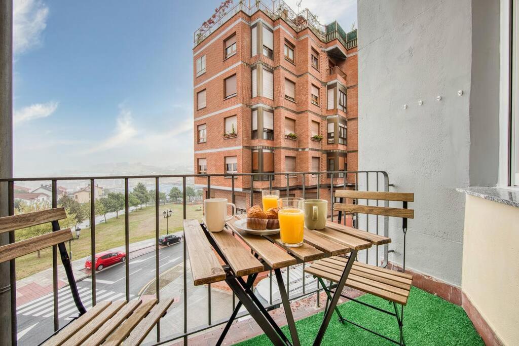 a balcony with a wooden table with orange juice at 642A Apartamento con vistas en Oviedo in Oviedo