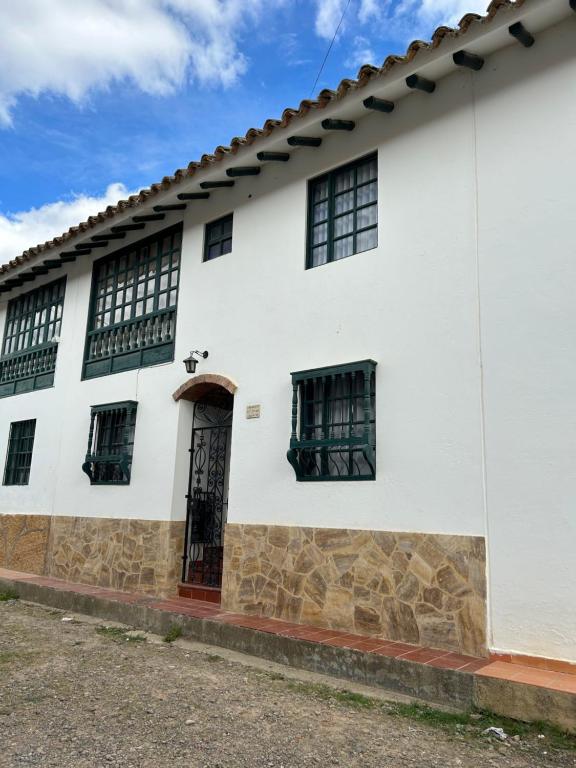 een wit gebouw met ramen en een deur bij Acogedora casa en Villa de Leyva in Villa de Leyva