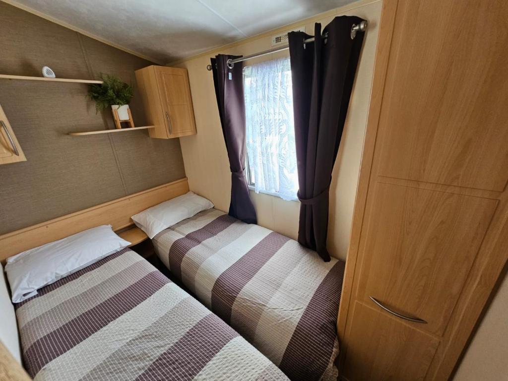 a small room with two beds and a window at NEW Orla Caravan in Meliden