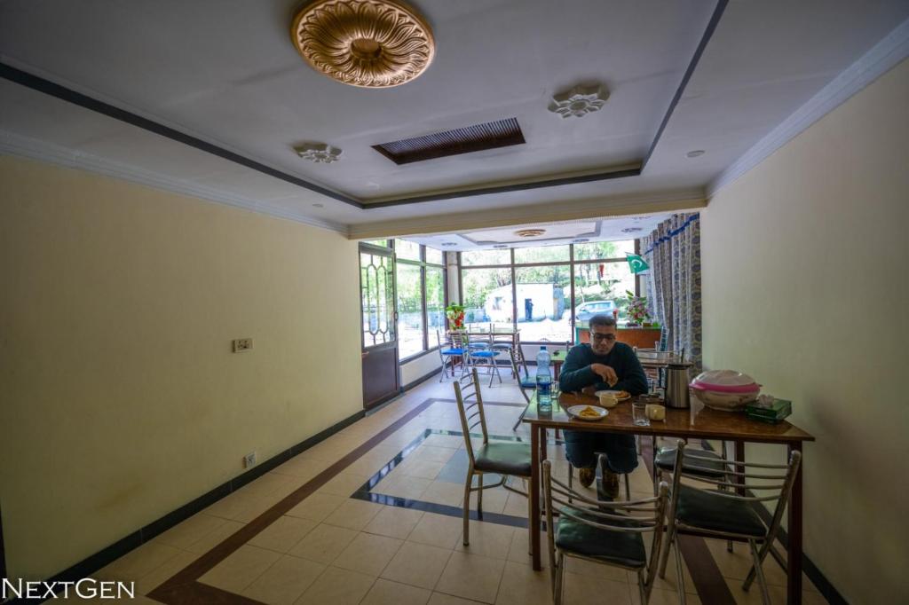 un hombre sentado en una mesa en una habitación en Green One Hotel, en Ponedas