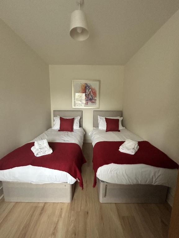 una camera con due letti con lenzuola rosse e bianche di Kensington Park a Reading