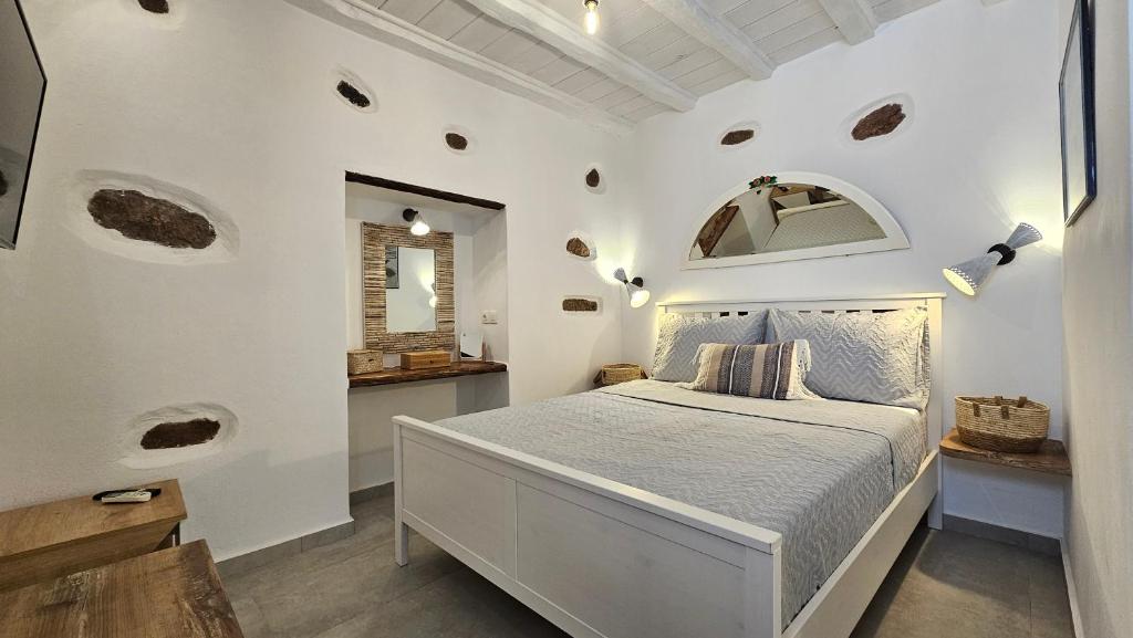 Un dormitorio blanco con una cama y un espejo. en Marmara Traditional Apartments, en Plaka Milou