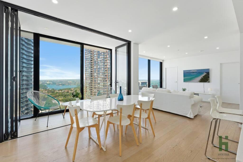 uma sala de estar com uma mesa e cadeiras e um sofá em St Leonards 2B2B Apt with Skyview em Sydney
