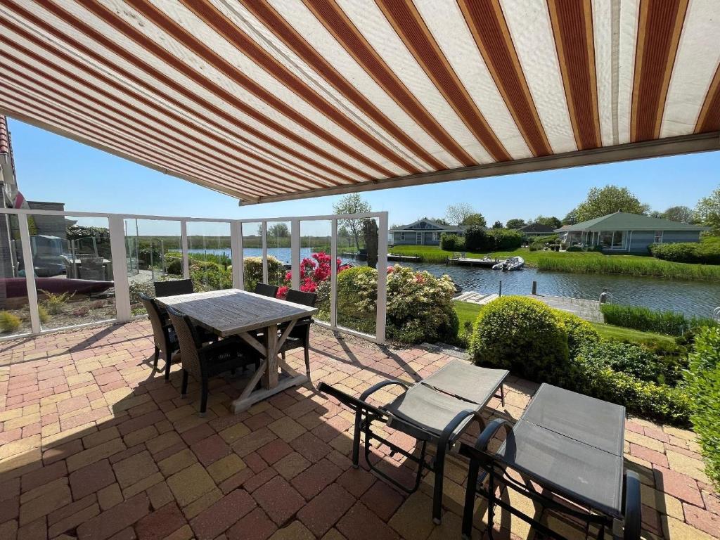 eine Terrasse mit einem Tisch und Stühlen sowie Flussblick in der Unterkunft Ferienhaus in Makkum Terrasse und Sauna in Makkum
