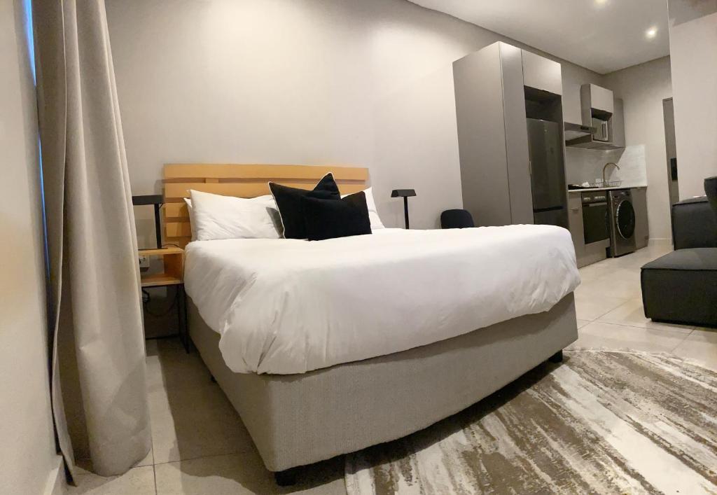 1 dormitorio con 1 cama grande con sábanas y almohadas blancas en Blackbrick Sandton two no-loadshedding en Johannesburgo