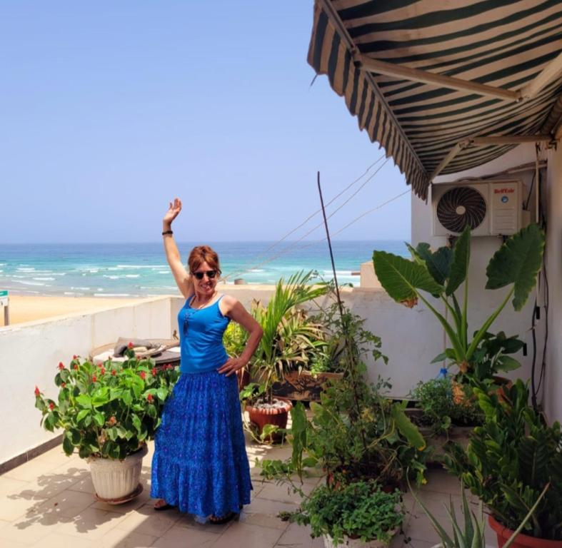 a woman in a blue dress standing in front of the beach at Casa Djoko in Dakar