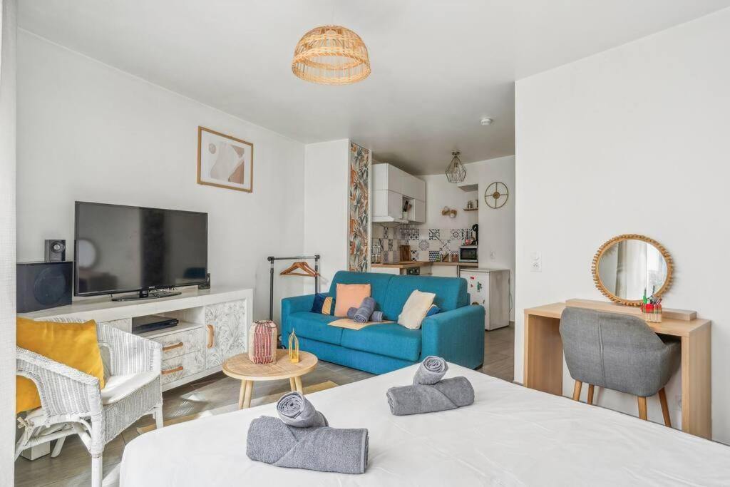 un salon avec un canapé bleu et une télévision dans l'établissement 10 minutes à pied du marché aux puces de Paris, à Saint-Ouen