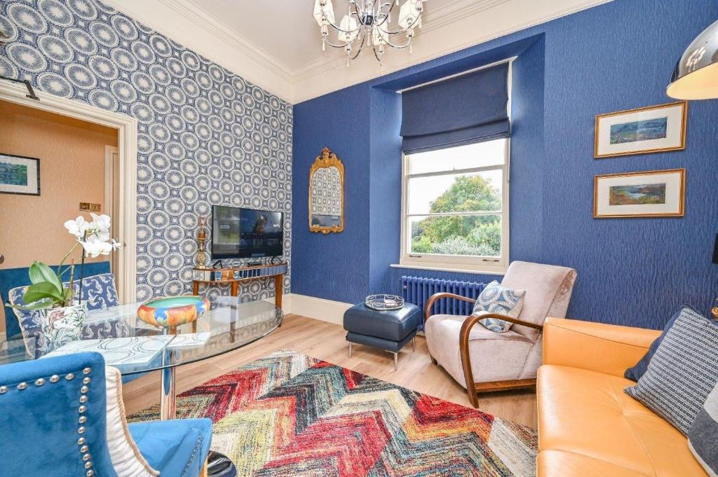 Elle comprend un salon doté de murs bleus et d'un lustre. dans l'établissement Große Wohnung in Torquay mit Terrasse, Grill und Garten, à Torquay