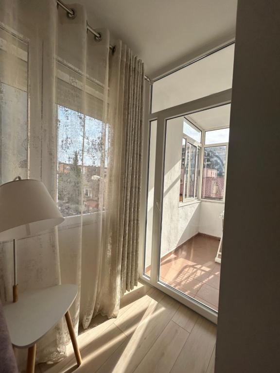Habitación con ventana grande con mesa y lámpara. en New Bazar Retreat Apartment, en Tirana