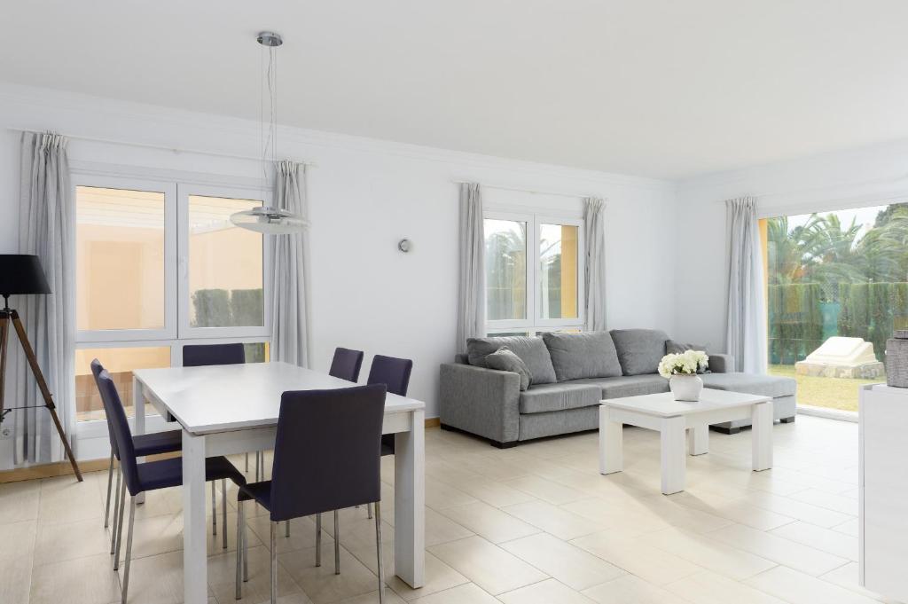 a white living room with a table and a couch at Seraph by ON Travel in Oliva