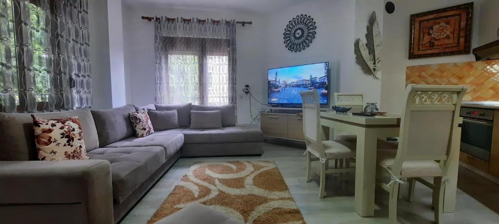 ein Wohnzimmer mit einem Sofa, einem Tisch und einem TV in der Unterkunft Fjori's Apartment in Korçë