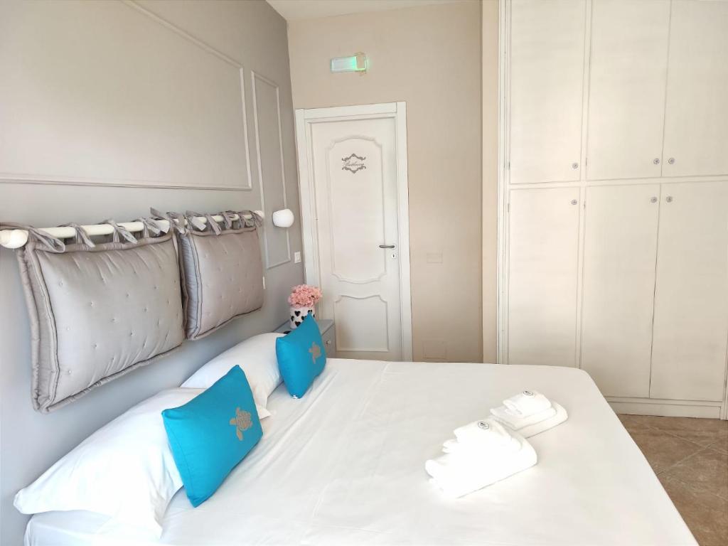 una camera da letto con un letto bianco con cuscini blu di Villa Antonietta Ischia a Ischia