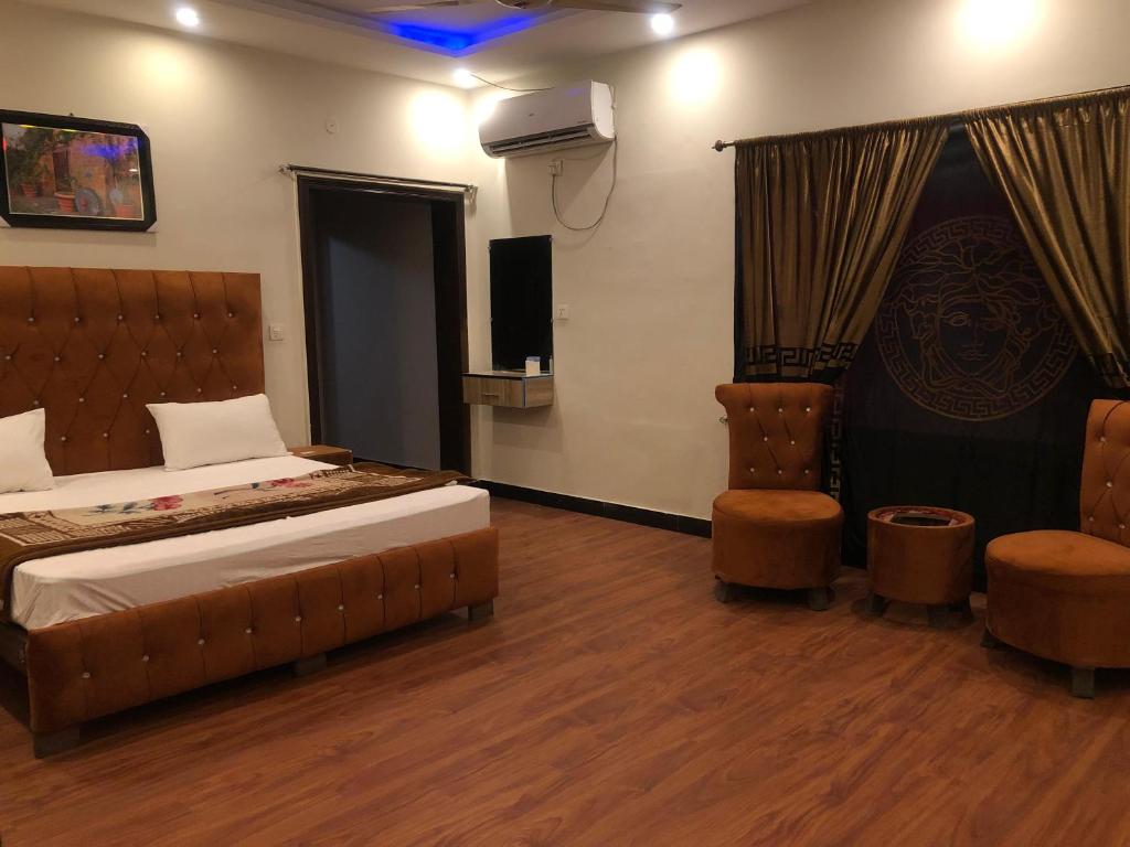 Defence-Mark-Hotel في لاهور: غرفة نوم بسرير وتلفزيون وكرسيين
