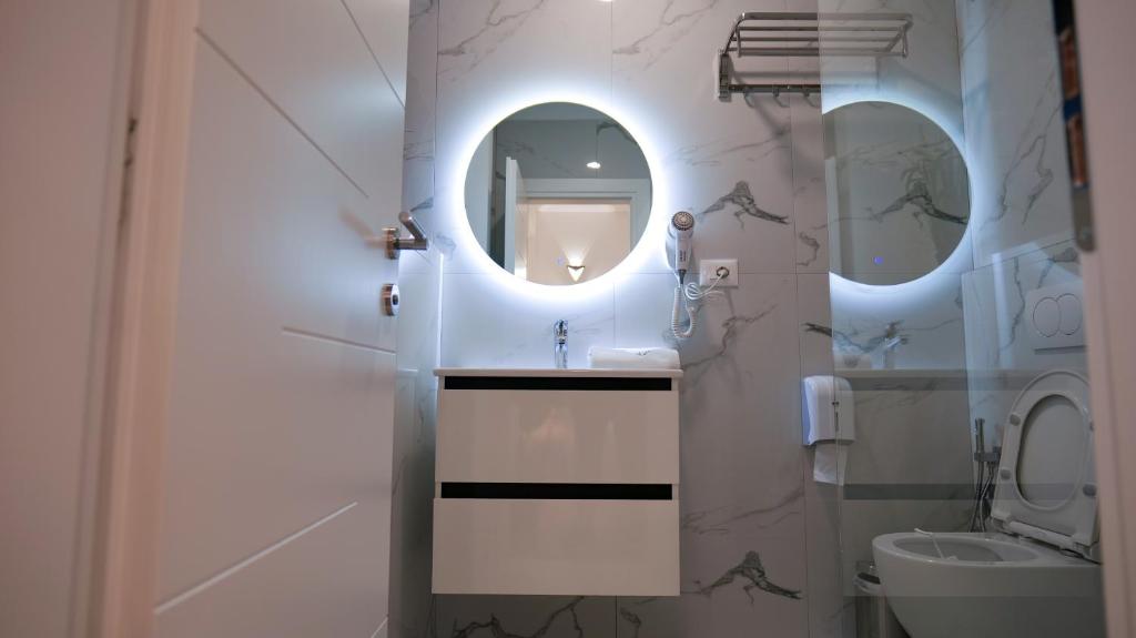 La salle de bains est pourvue d'un lavabo, d'un miroir et de toilettes. dans l'établissement 313 Villa City Center Hotel, à Tirana