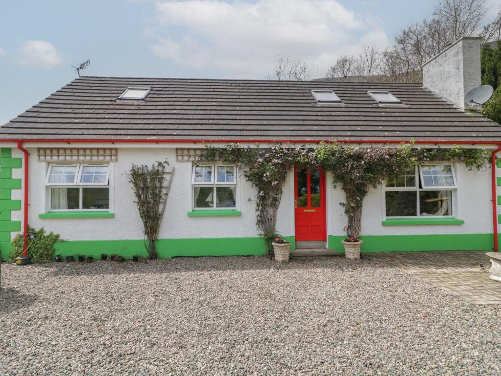 une maison blanche et verte avec une porte rouge dans l'établissement Gortin Cottage, à Ballymena