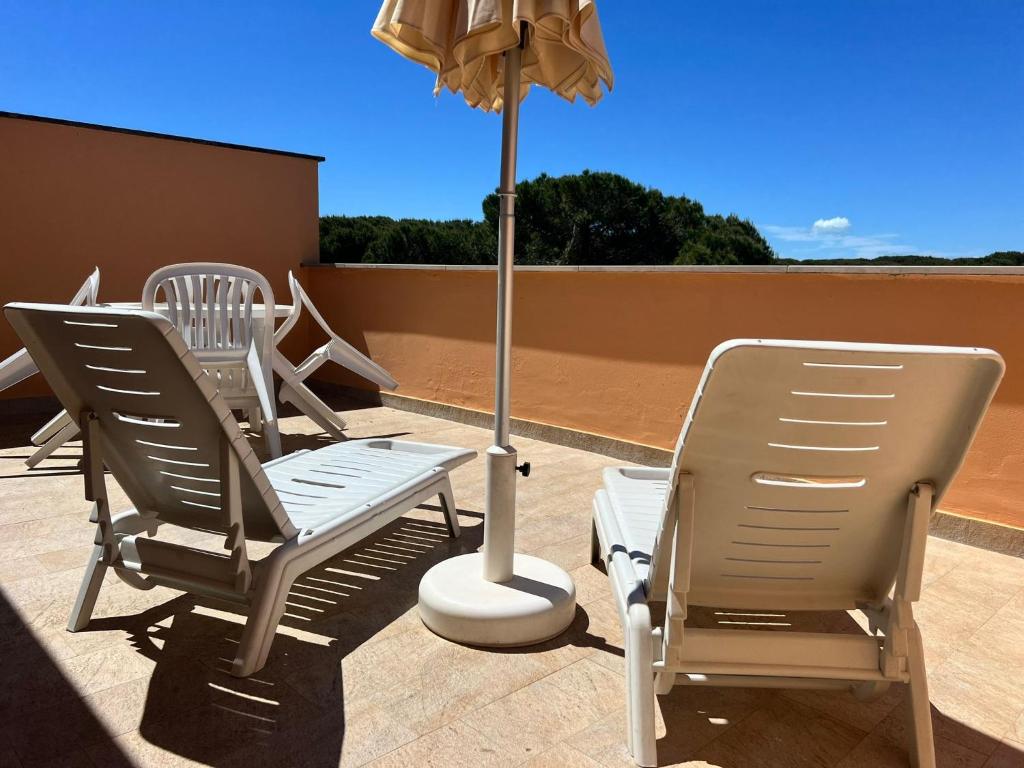 trzy krzesła i parasol na patio w obiekcie Sofis Servizi Rio Grande (CAV) w mieście Principina a Mare