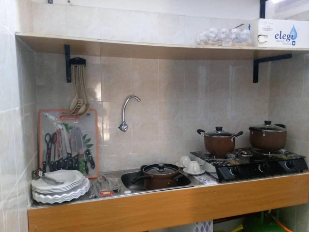 encimera de cocina con fogones, ollas y sartenes en Kondjikpé, en Cotonou
