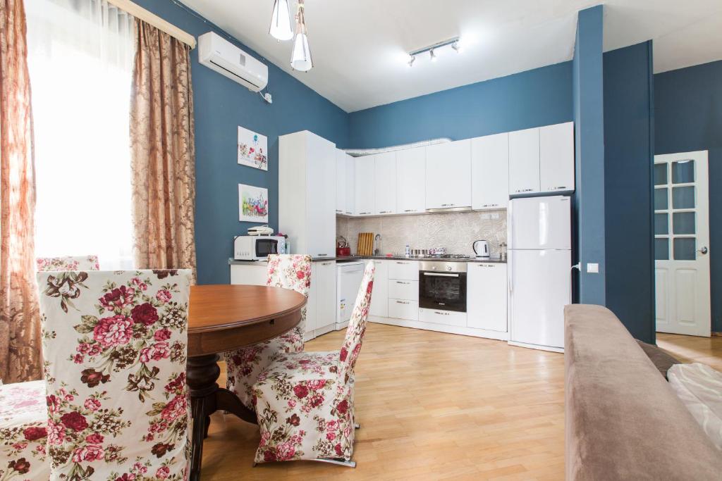 a kitchen with blue walls and a wooden table and chairs at Sweet Home Freedom Square in Tbilisi City
