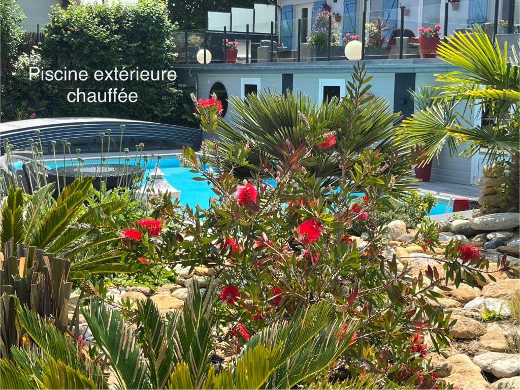 un jardín con flores rojas y una piscina en Hotel la piscine en Villers-sur-Mer