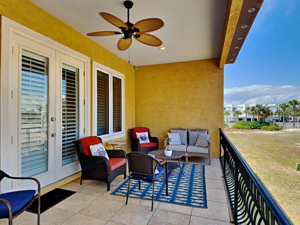 - une terrasse couverte avec des chaises, une table et un ventilateur de plafond dans l'établissement Regency Cabanas h6, à Pensacola Beach