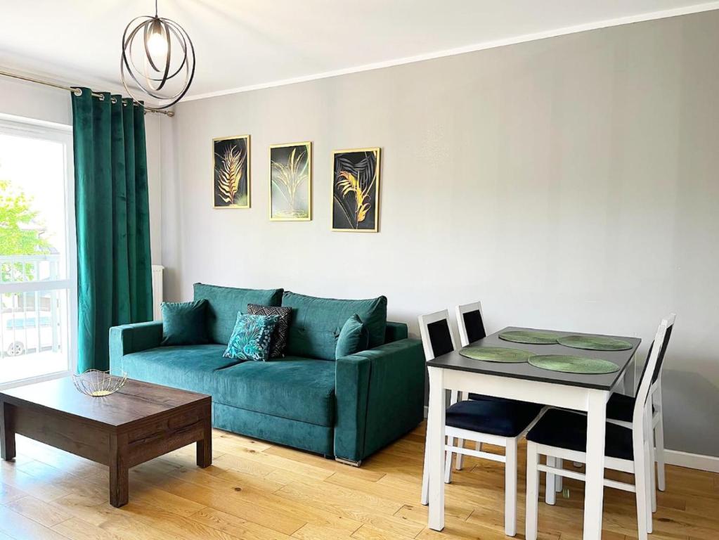 uma sala de estar com um sofá verde e uma mesa em Apartament Odpoczynek em Ustrzyki Dolne