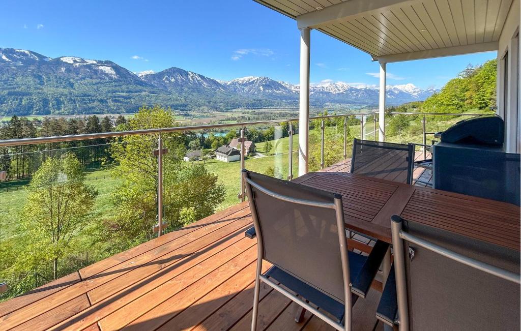a deck with a table and chairs and mountains at Chalet Mit Karawankenblick in Köttmannsdorf