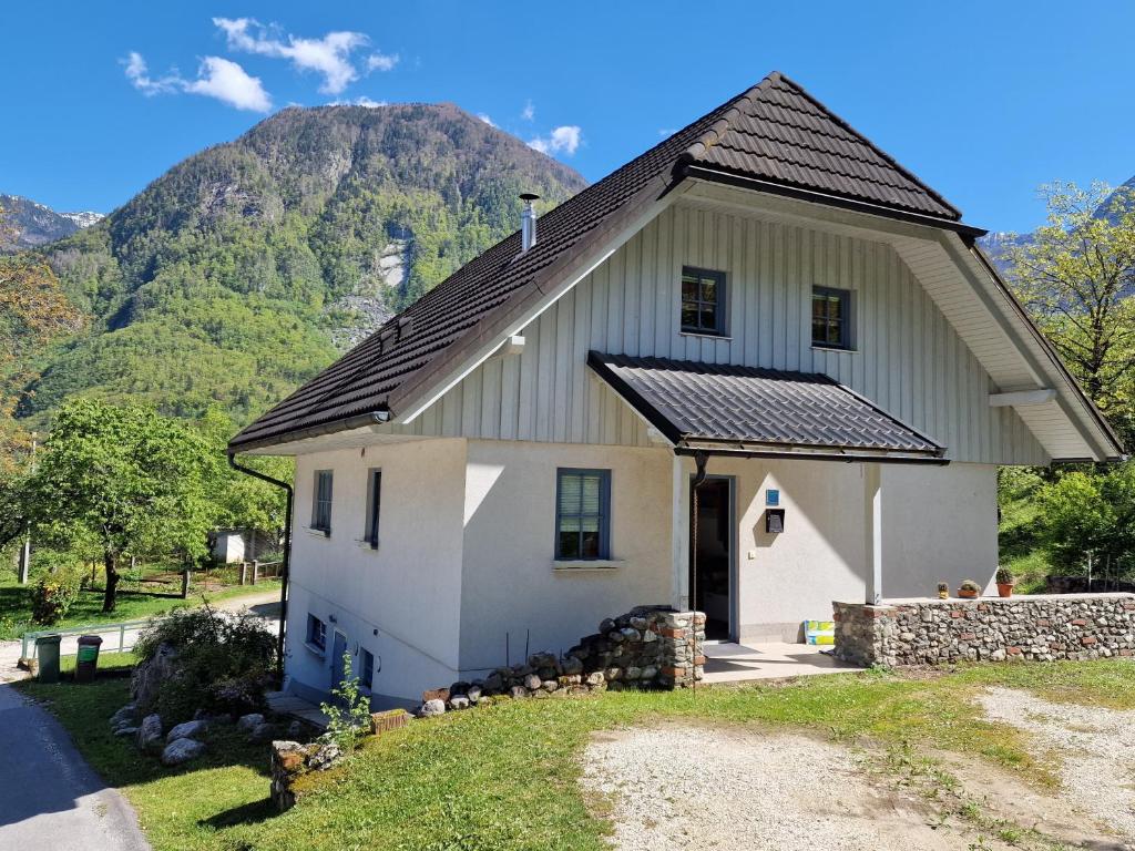 a white house with a mountain in the background at Apartment Luka at Soča & Koritnica confluence in Bovec