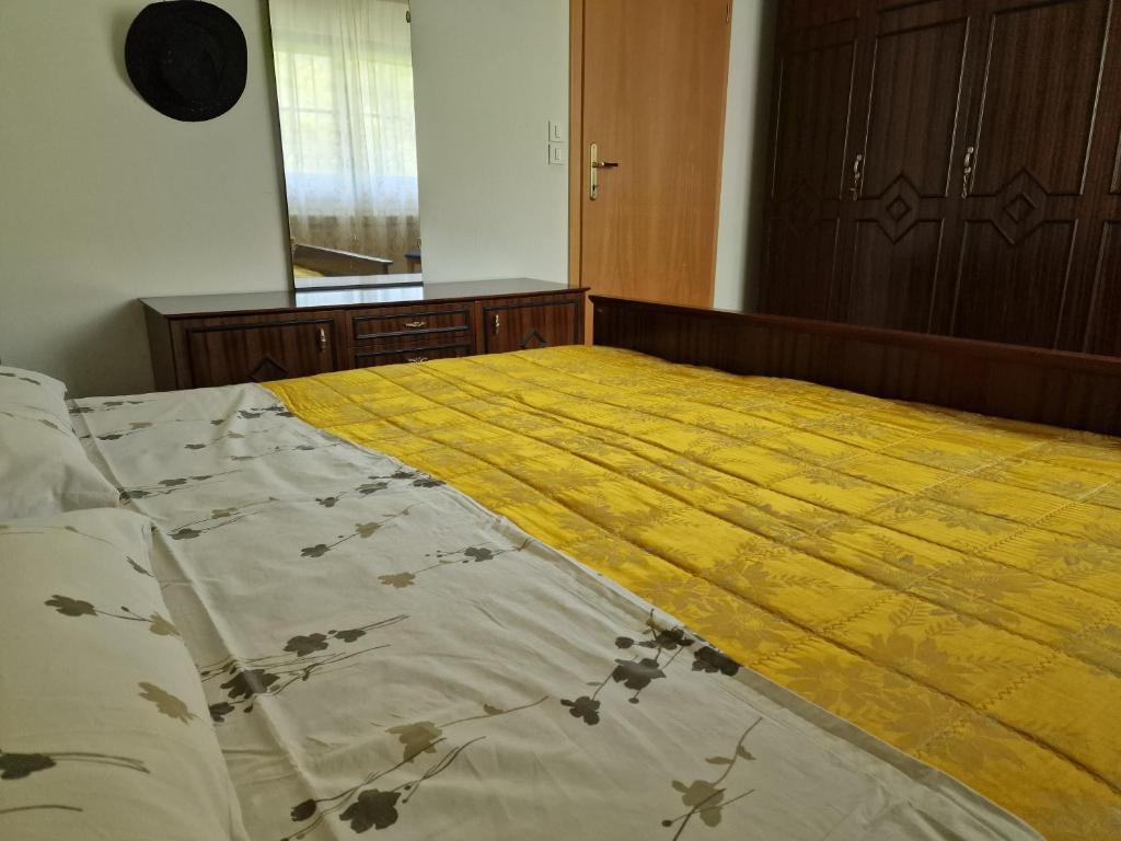 a large bed with a yellow blanket on it at Apartment Luka at Soča & Koritnica confluence in Bovec