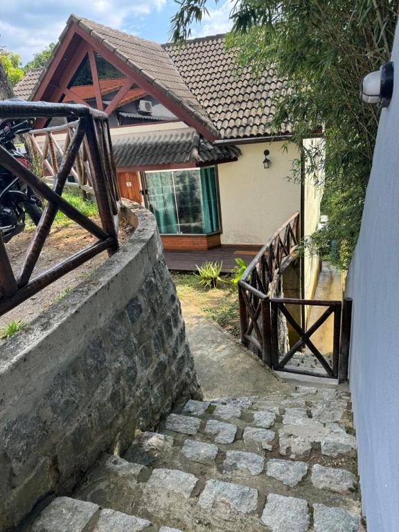 um caminho de pedra que leva a uma casa com um portão de madeira em Chalé 08 com hidro no coração de Penedo em Itatiaia