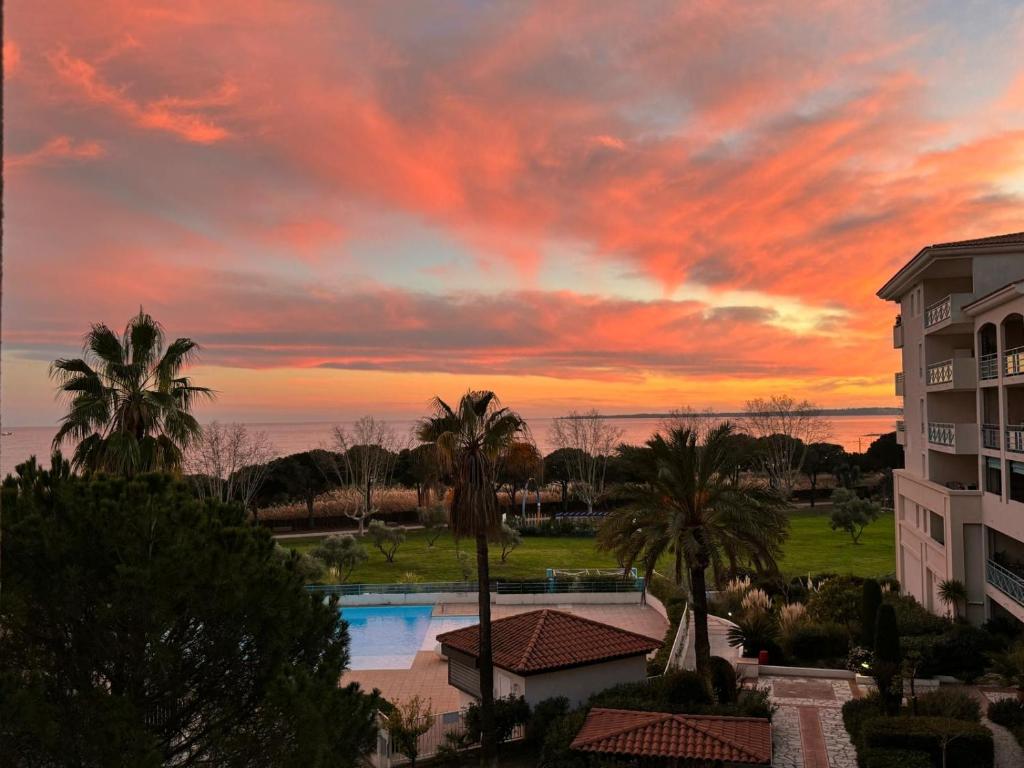 - un coucher de soleil au-dessus d'une piscine dans un complexe avec des palmiers dans l'établissement Bellissimo Appartamento Vistamare, à Antibes