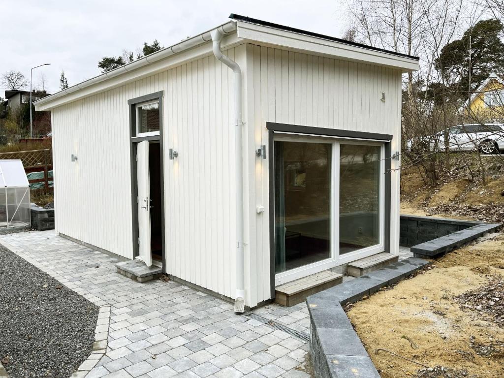 um pequeno edifício branco com uma grande porta de vidro em Newly built Attefall house located in Tumba just outside Stockholm em Tumba