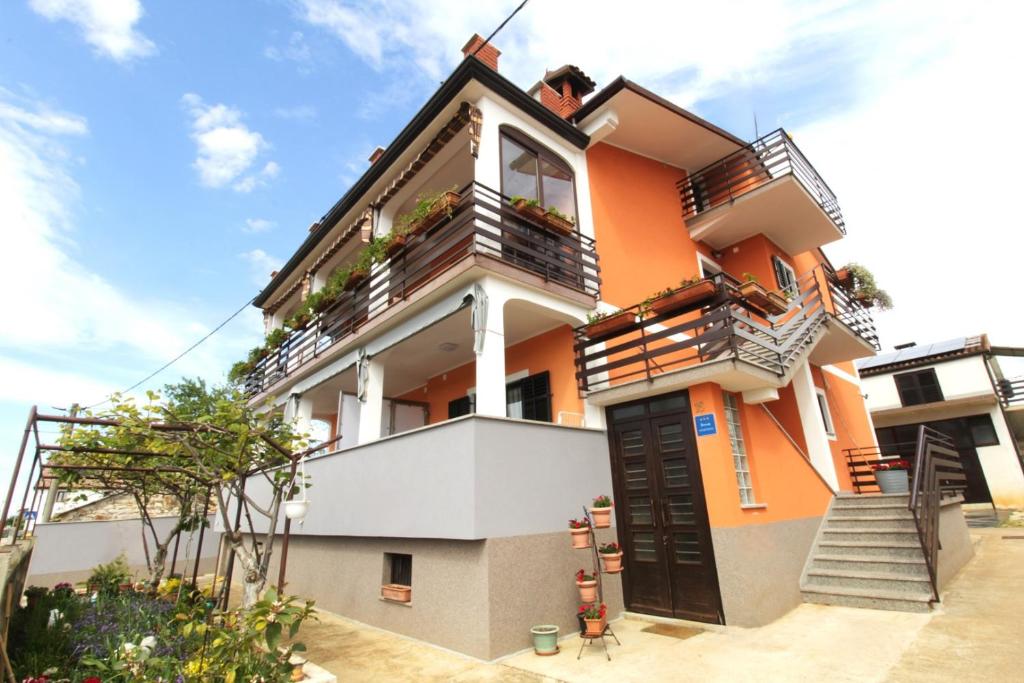 een oranje en wit huis met trappen en balkons bij Apartments Tre pini in Umag