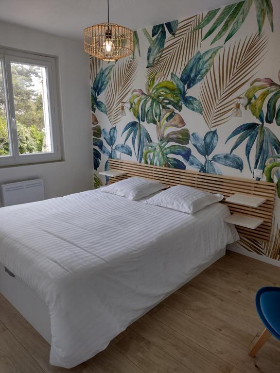 a bedroom with a large white bed with floral wallpaper at Appartement avec vue mer in Vaux-sur-Mer