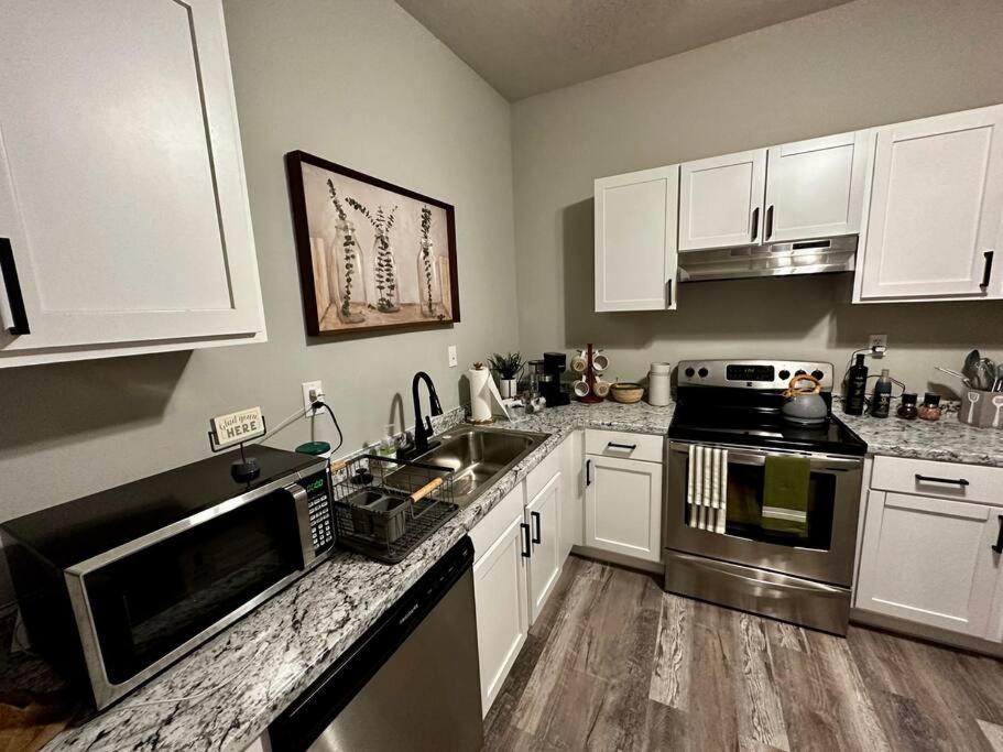 una cocina con armarios blancos y electrodomésticos de acero inoxidable en Boho Bungalow near TU/DT/Cherry St/Expo Center, en Tulsa