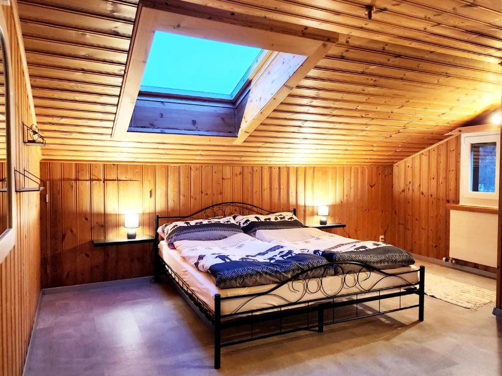 Cama en habitación de madera con tragaluz en Ferienwohnung in perfekter Lage in der Surselva en Trun