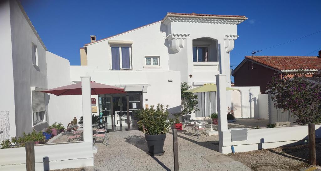 a white building with a patio in front of it at Hôtel le Calypso in Hyères