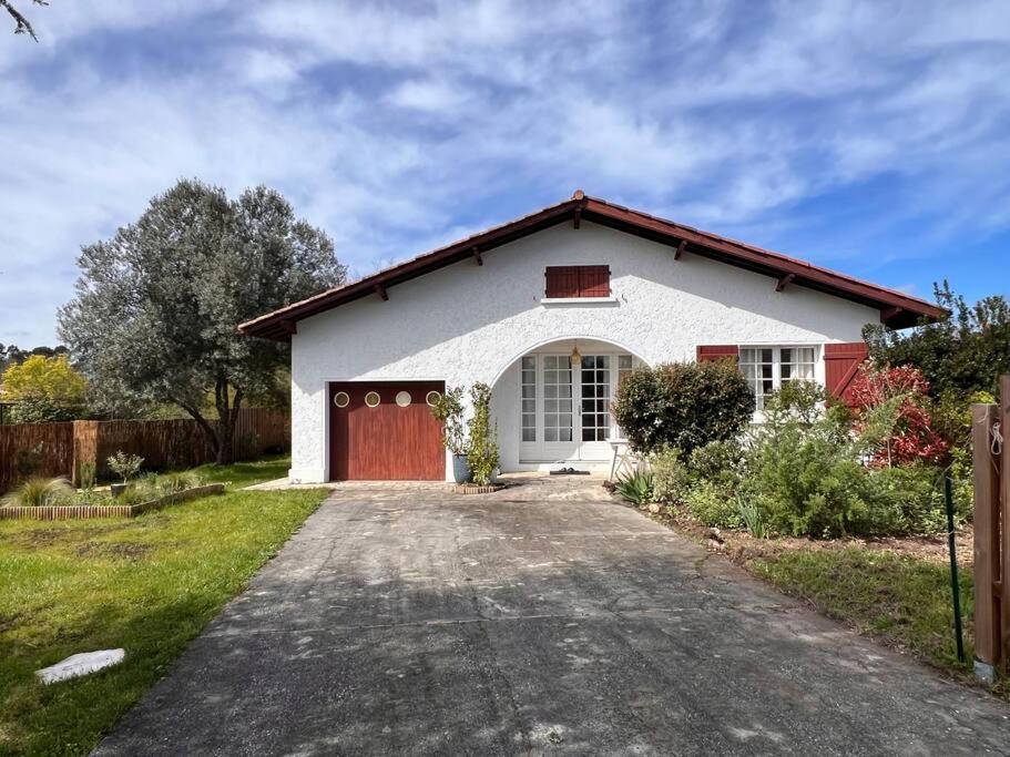 une maison blanche avec une porte rouge et une allée. dans l'établissement Agréable Maison Landaise proche du Lac, à Sanguinet